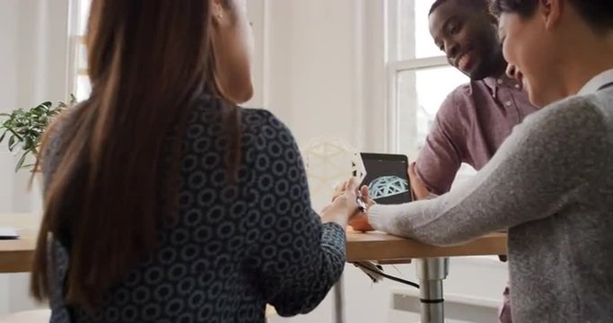 Business woman using tablet app showing 3d printed model of geodesic dome walking through modern office to diverse team meeting