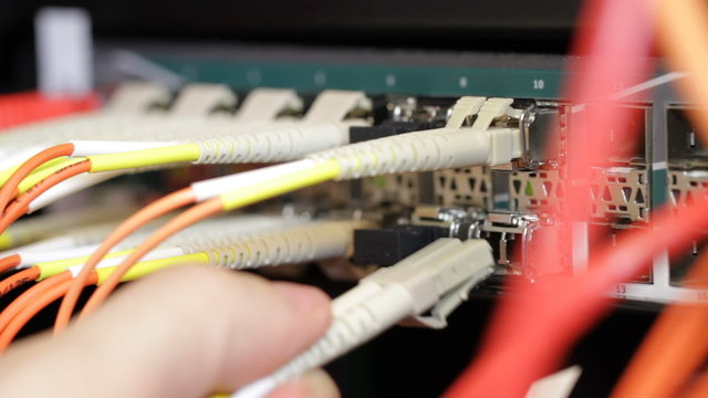 IT consultant insert fiber channel network cable into switch