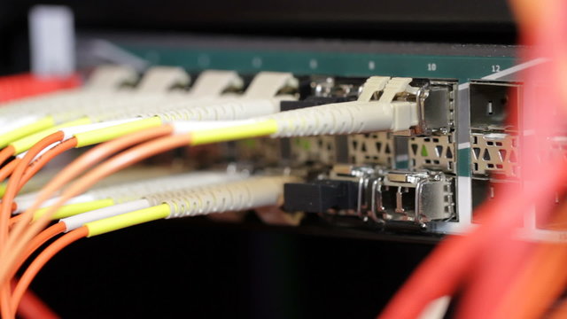 IT technician insert fiber channel cable into network switch