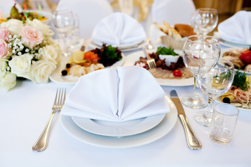 Table in a restaurant with wine glasses, white napkins and cutlery