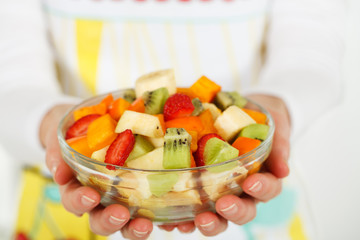 Fruit salad in the hands of women.