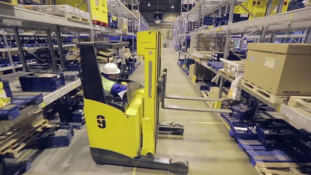 Adult worker on autoloader taking box from metal rack.