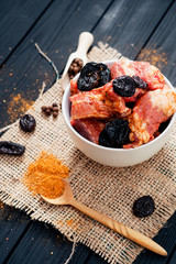 raw meat marinated in spices and pepper pork ribs with prunes in a deep bowl for the grill or barbecue on a wooden background 
