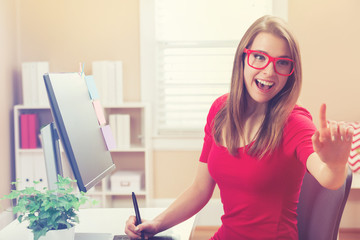 Young woman working with a pen tablet in her home office