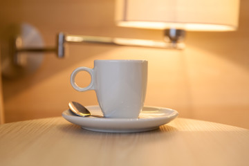 cup of coffee on wooden table at the hotel with a lamp in the ba