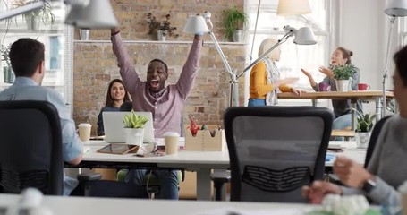 Businessman with arms raised celebrating success watching sport victory on laptop diverse people group clapping expressing excitement in office