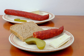 Sausages with a slice of bread, cheese and pickle on a plate