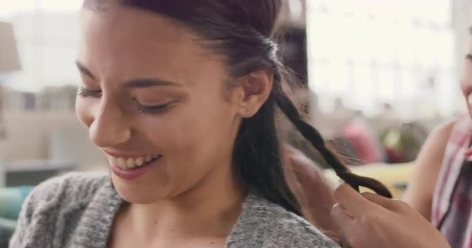 Multi Racial Girl Friends Braiding Hair Smiling Using Mobile Phone Hanging Out On Sofa 