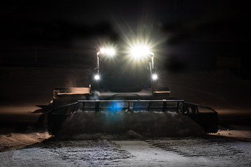 Snowcat preparing a slope at night 