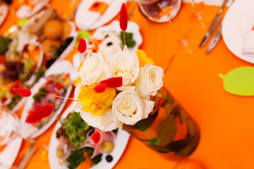 Wedding table with flower composition decorated in orange colors 