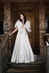 Fototapeta premium The bride in a fur cape on a porch of a wooden house