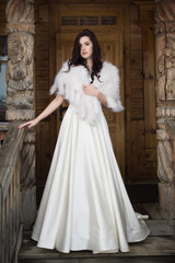 Obraz premium The bride in a fur cape on a porch of a wooden house