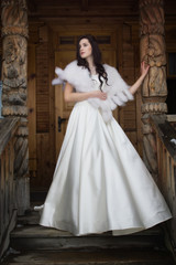 Fototapeta premium The bride in a fur cape on a porch of a wooden house