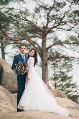 Gorgeous bride, groom kissing and hugging near the cliffs with stunning views