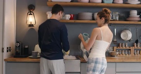 Newly wed in love couple dancing at home washing dishes wearing pajamas having fun