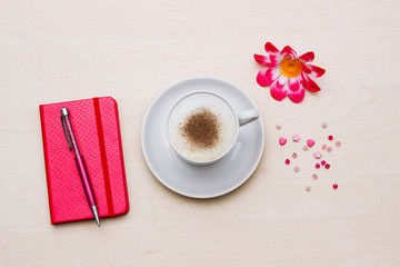Notebook with cup of coffee and flower on wooden