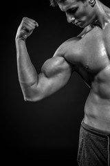 Fototapeta na wymiar Fitness man showing his triceps, biceps muscles on black backgro