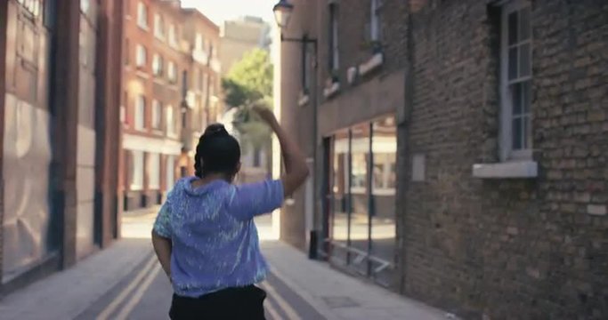 Contemporary funky African American woman street dancer dancing freestyle in the city