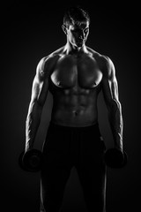 Fototapeta na wymiar Muscular man showing perfect body with dumbbells on black backgr