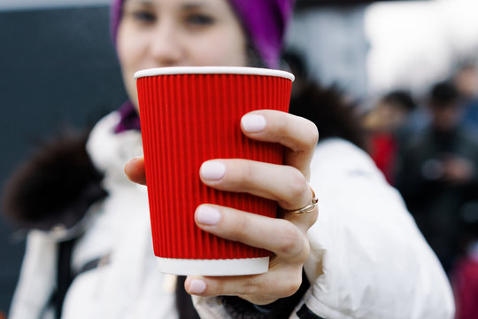 Girl holds a red cup of hot tea