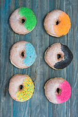 Hand decorated artisan donuts on wooden rustic table, from above