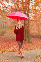 Fashion woman with umbrella relaxing in fall park.