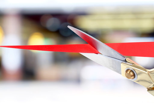 Scissors cutting red ribbon close up