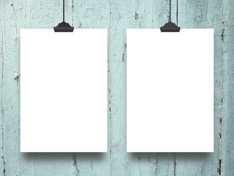 Close-up of two hanged paper sheets with clips on aqua wooden boards background