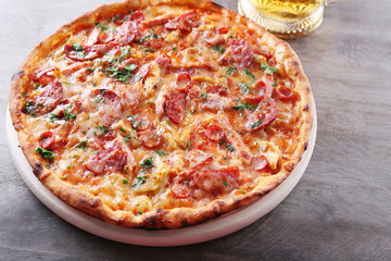 Tasty pizza and glass of beer are on wooden table, close up