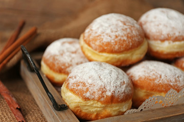 Delicious sugary donuts in wooden tray closeup