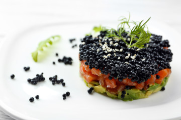 Delicious salmon tartare with black caviar on white plate - obrazy, fototapety, plakaty