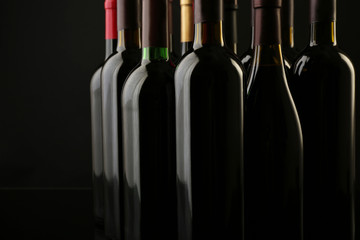 Wine bottles in a row on black  background, close up