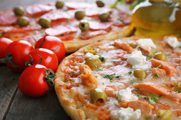 Delicious tasty pizzas with ingredients on table, closeup