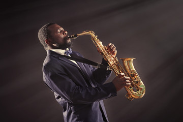 Naklejka premium African American jazz musician playing the saxophone on grey background