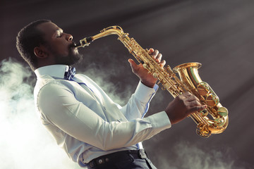 Fototapeta na wymiar African American jazz musician playing the saxophone against smoky background