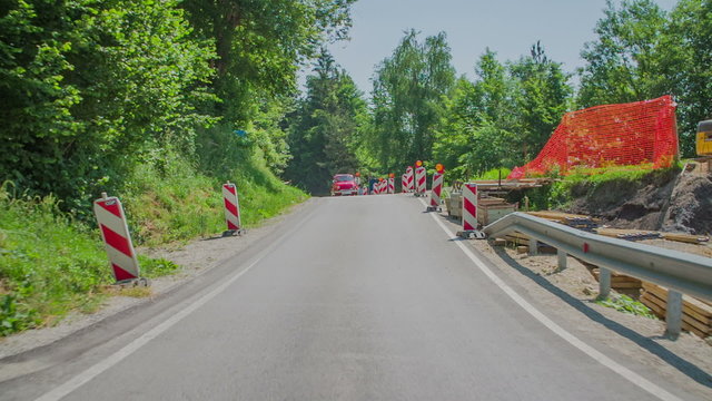 Red vintage zastava is driving downhill and passing the road works