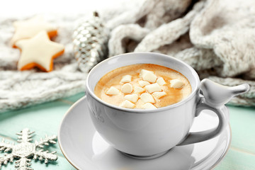Cup of hot cacao with marshmallow, cookies and warm scarf on blue table