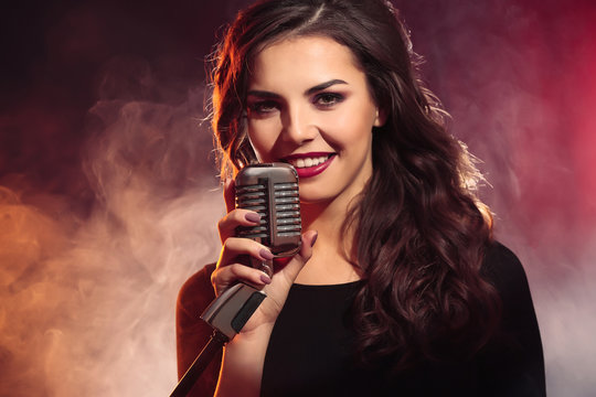 Beautiful singing woman on red background in the smoke, close up