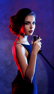 Beautiful brunette woman singing on purple background