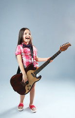 Beautiful artistic little girl playing guitar on grey background