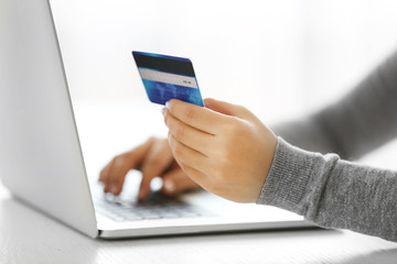 E-commerce concept. Woman with credit card and laptop, close up