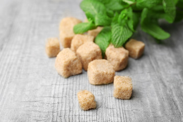 Pile of brown sugar cubes and stevia  on grey wooden background