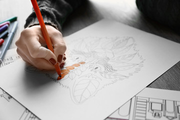 Female hand painting anti stress colouring with orange felt pen