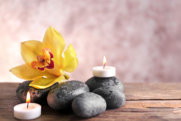 Spa still life with stones, flower and candlelight on blurred pastel background