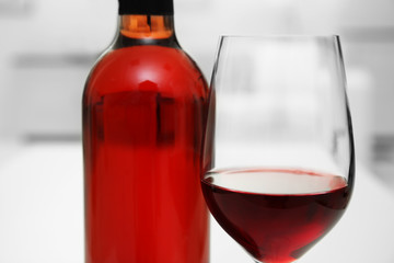 Glass of red wine with bottle on blurred interior background
