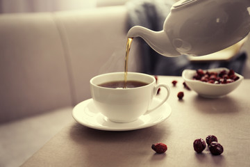 Pouring rose hip tea into cup, home atmosphere