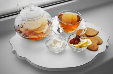 Tea set on a white wooden mat on the windowsill