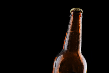 Glass bottle of beer on black background