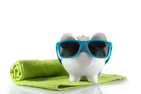 Piggy bank with towel and sunglasses, isolated on white. Holiday money concept