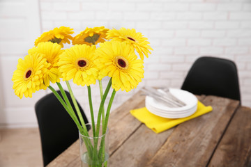 Beautiful bouquet of yellow gerbera flowers and utensils on wooden table